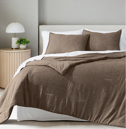Bed with brown bedding and white pillows in a bedroom setting.