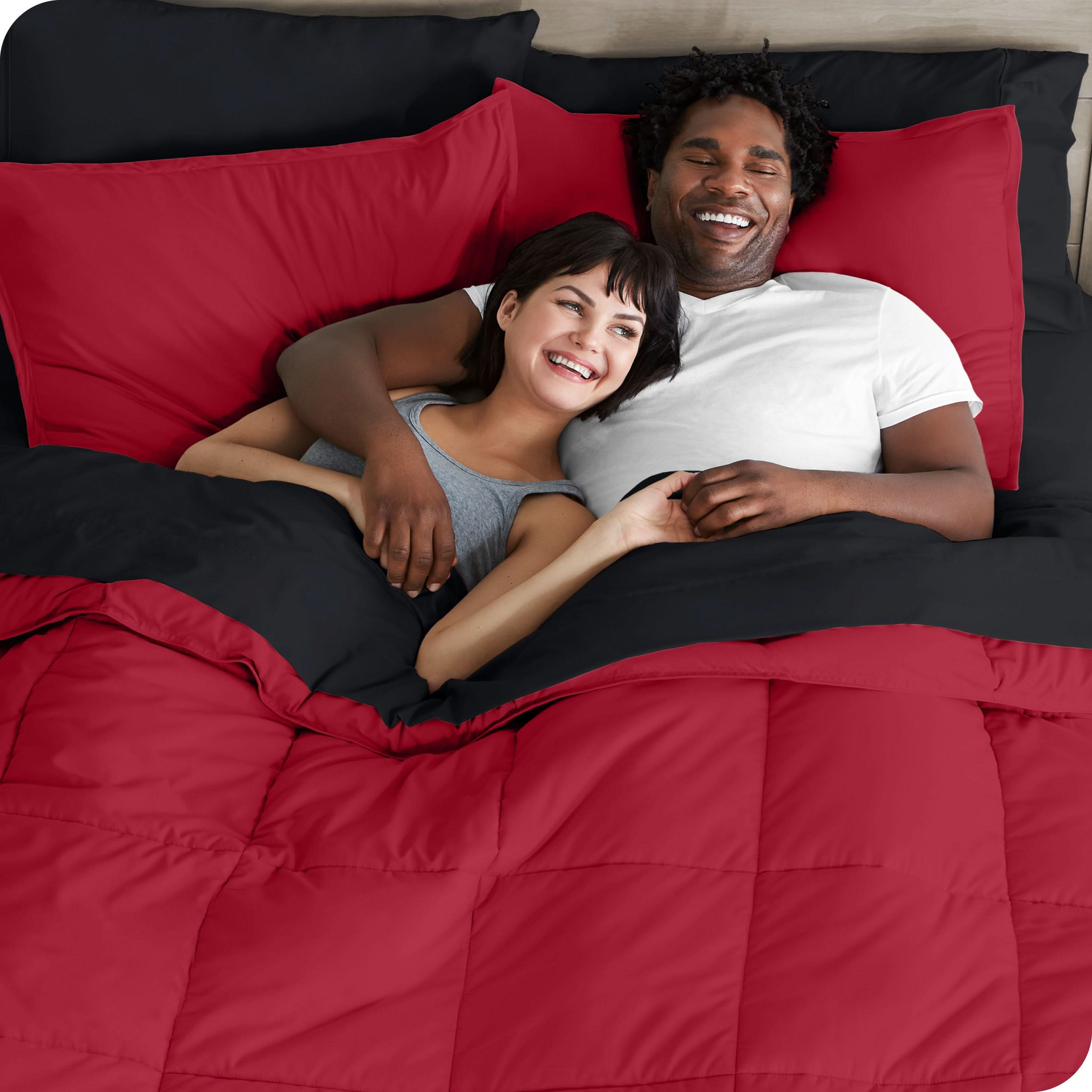 A couple is lying in bed with a comforter and sheets over them