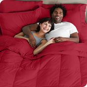 A couple is lying in bed with a comforter and sheets over them