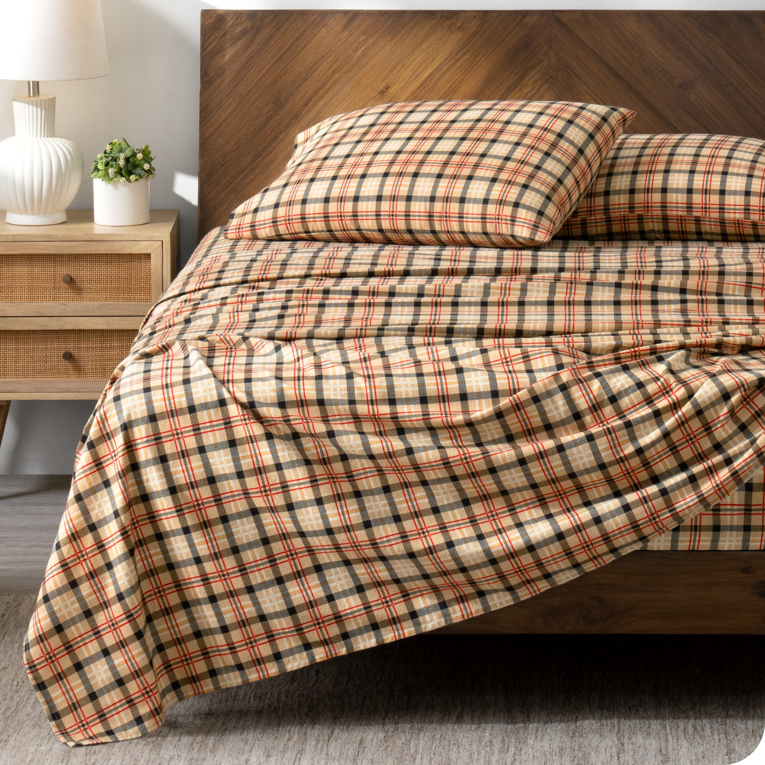 Wooden bed frame with flannel print sheets on the bed