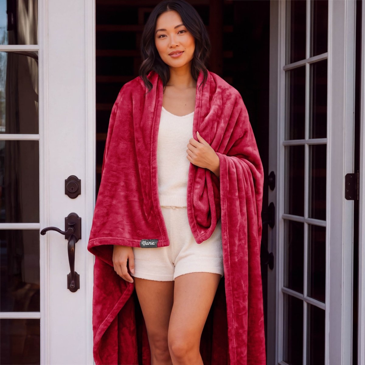 A woman standing with a microplush blanket wrapped around her
