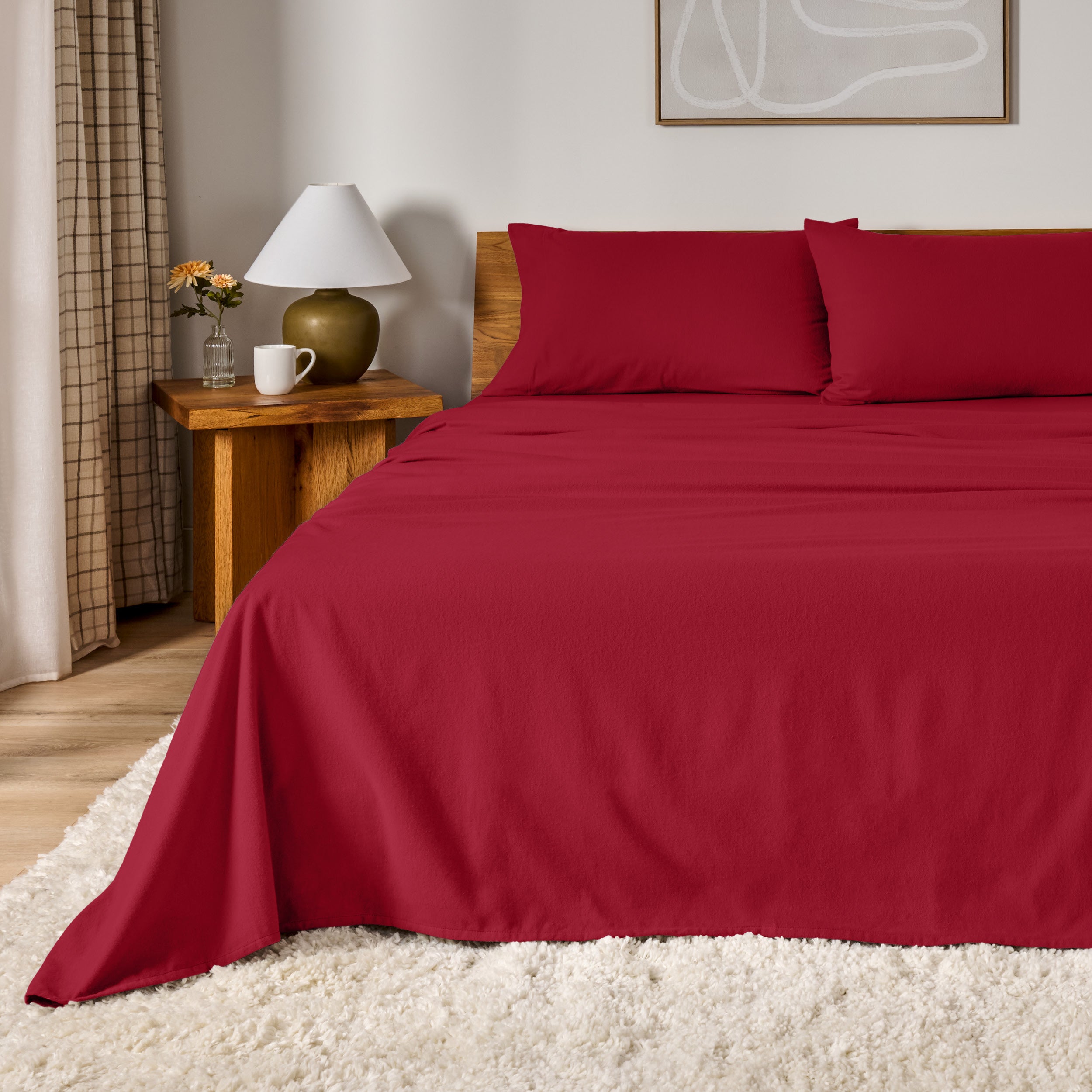 A bed dressed in flannel sheet set in a bedroom with a wooden headboard, bedside table and lamp
