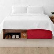 One side of a bed has shoes and a box under it while the other side has a bed skirt so that under the bed is hidden from view