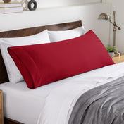 Bed sheets and pillows on a neatly made bed with a wooden headboard.