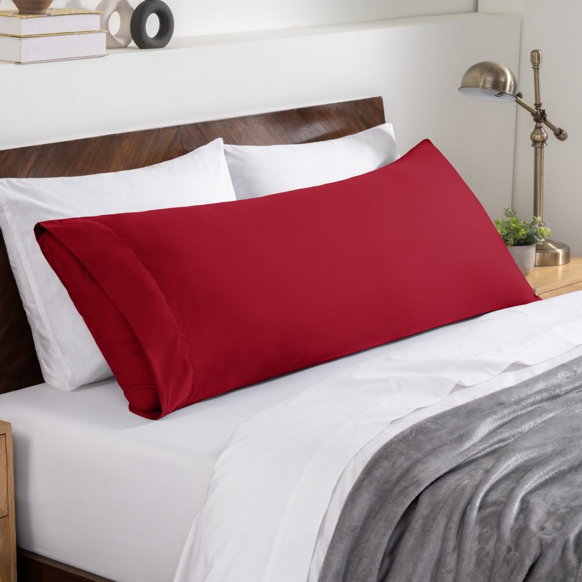 Bed sheets and pillows on a neatly made bed with a wooden headboard.