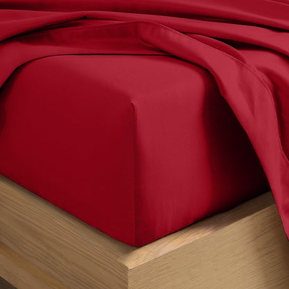 A close-up of a fitted sheet covering the corner of a bed frame, with matching top sheet draped over it.