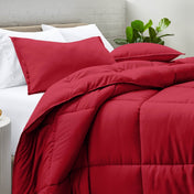 Comforter and pillow shams on a bed with a white brick wall and plant in the background