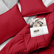 Comforter and pillows on a bed with a magazine and glasses.