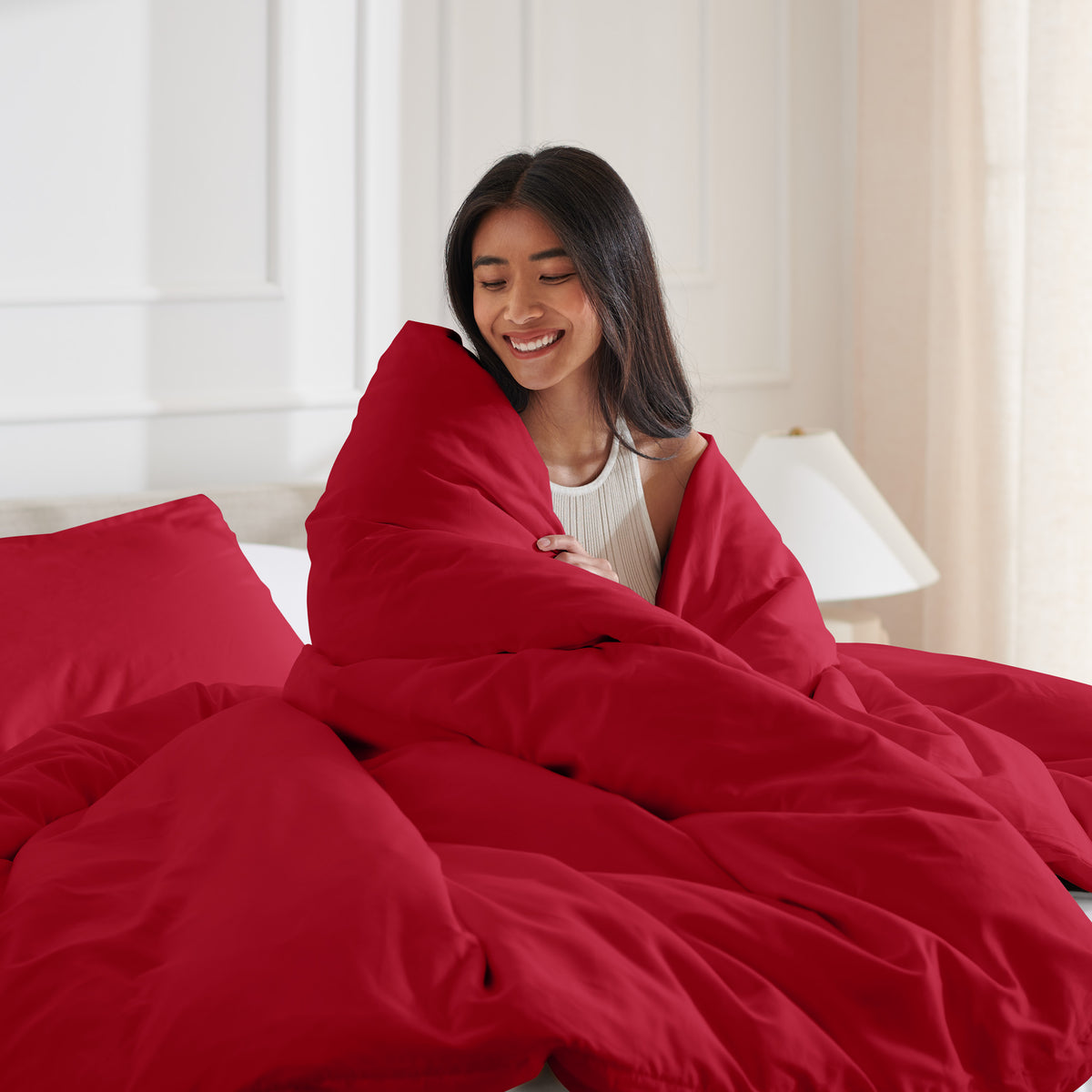 Woman smiling under duvet cover set in a bedroom setting