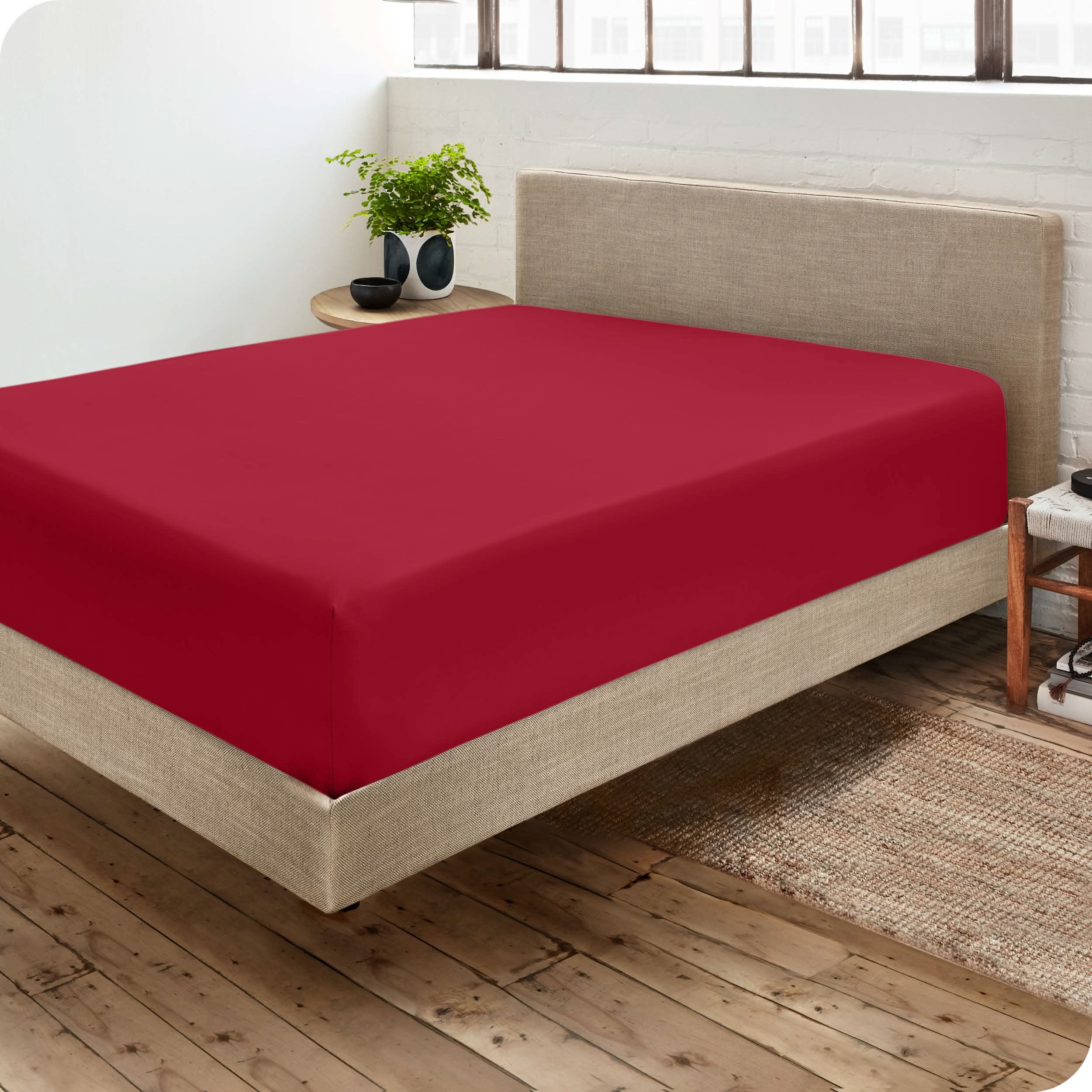 Bedroom with a microfiber fitted sheet on the mattress. A small nightstand is next to the bed with a plant and a bowl on it.