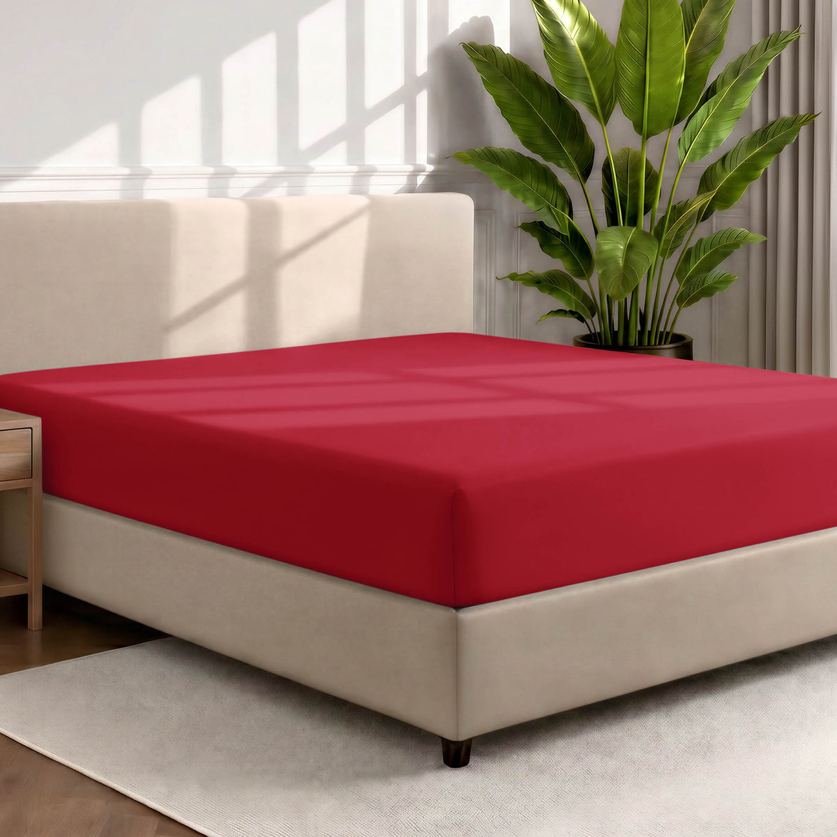 Bed with a fitted sheet in a room with a large plant and rug