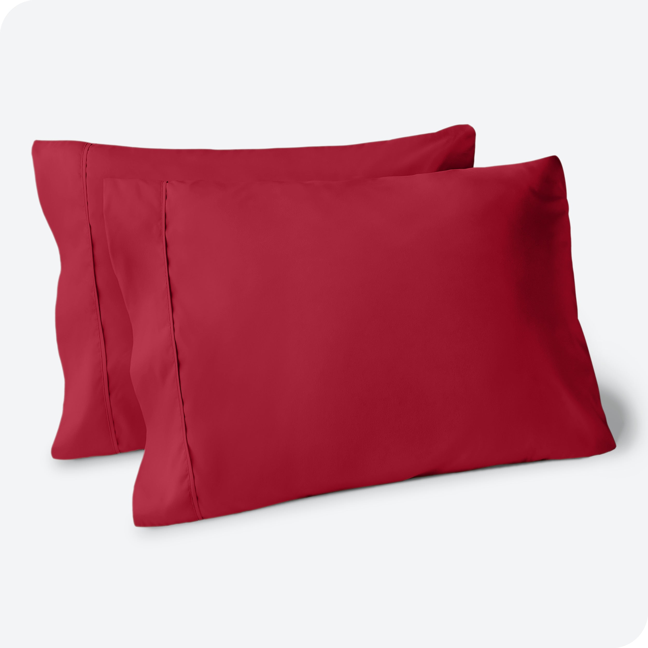 Two pillows on a white background with red pillowcases on them
