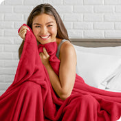 Woman sitting on a bed cuddling with a microplush blanket