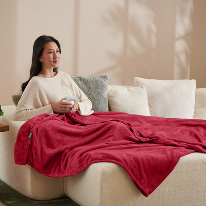 A woman sitting on a couch with a microplush blanket on her lap