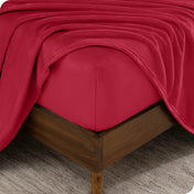 The corner of a bed frame and mattress with a fitted sheet and flat sheet on it.