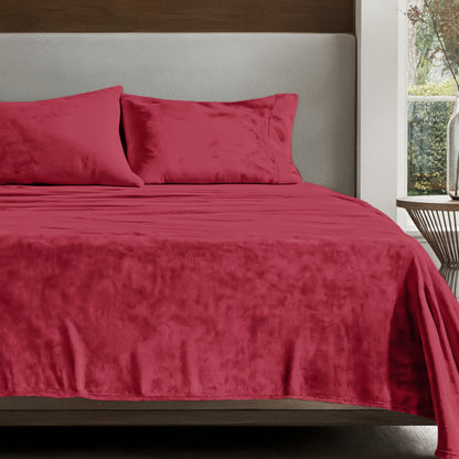 Microplush sheet set on a bed in a bedroom setting with a nightstand and lamp.