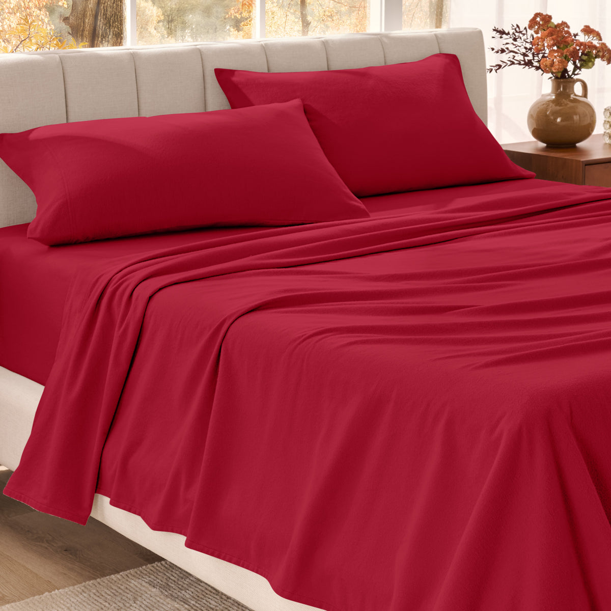 Bed sheets on a neatly made bed in a bright bedroom with large windows.