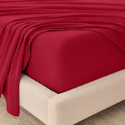 Fitted sheet and top sheet on a mattress with a beige bed frame