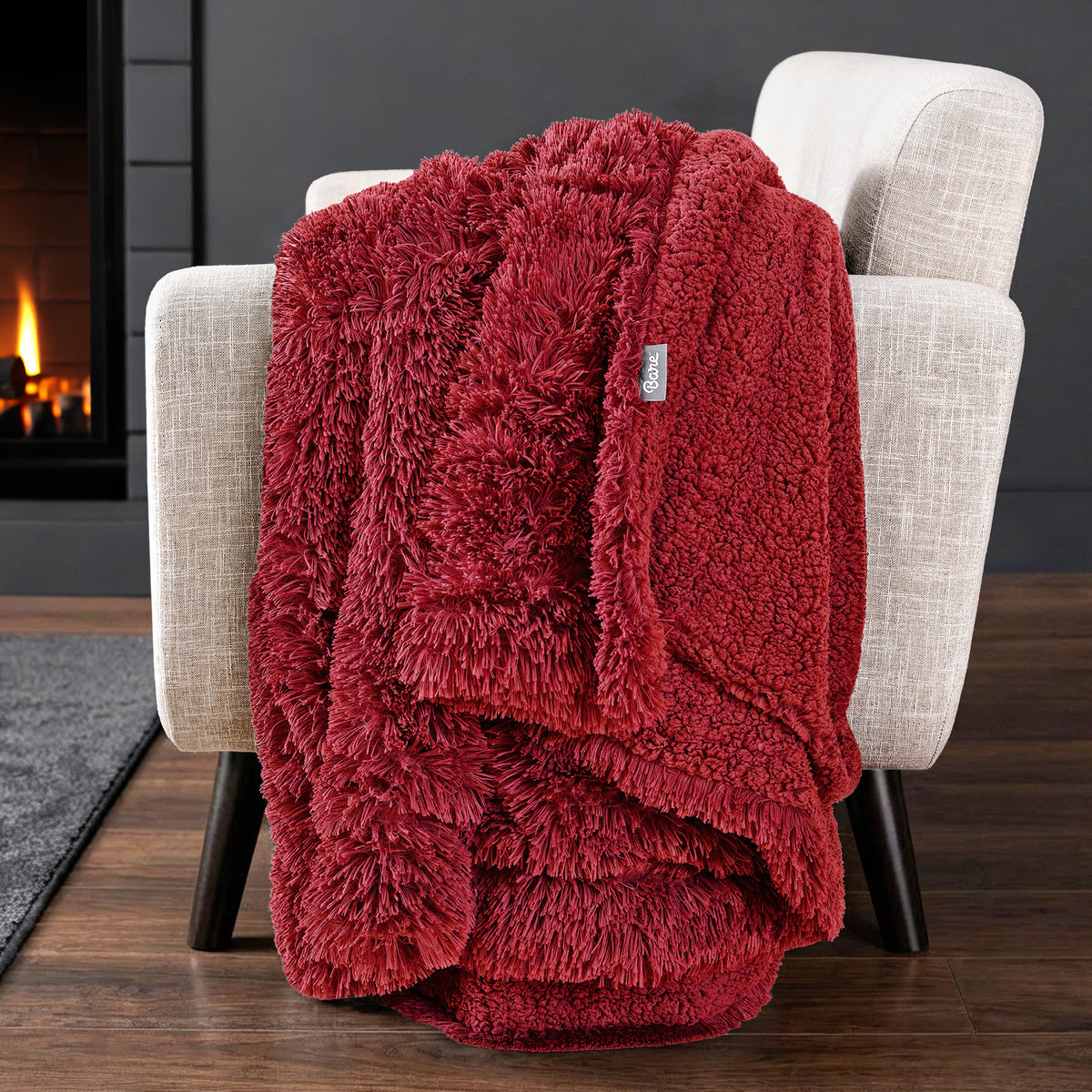 Sherpa blanket draped over an armchair in front of a fireplace.
