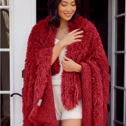 A woman standing with a shaggy blanket wrapped around her