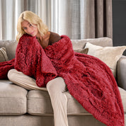 A woman sitting on a couch with a shaggy blanket wrapped around her