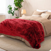 A shaggy faux fur blanket on the end of a bed