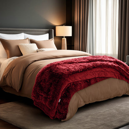A shaggy faux fur blanket at the end of a bed