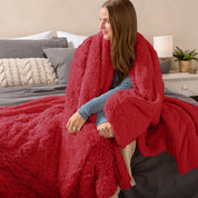 Fluffy blanket draped over a woman sitting on the end of a bed