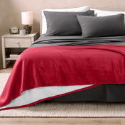 Bed with grey sheets and a sherpa blanket