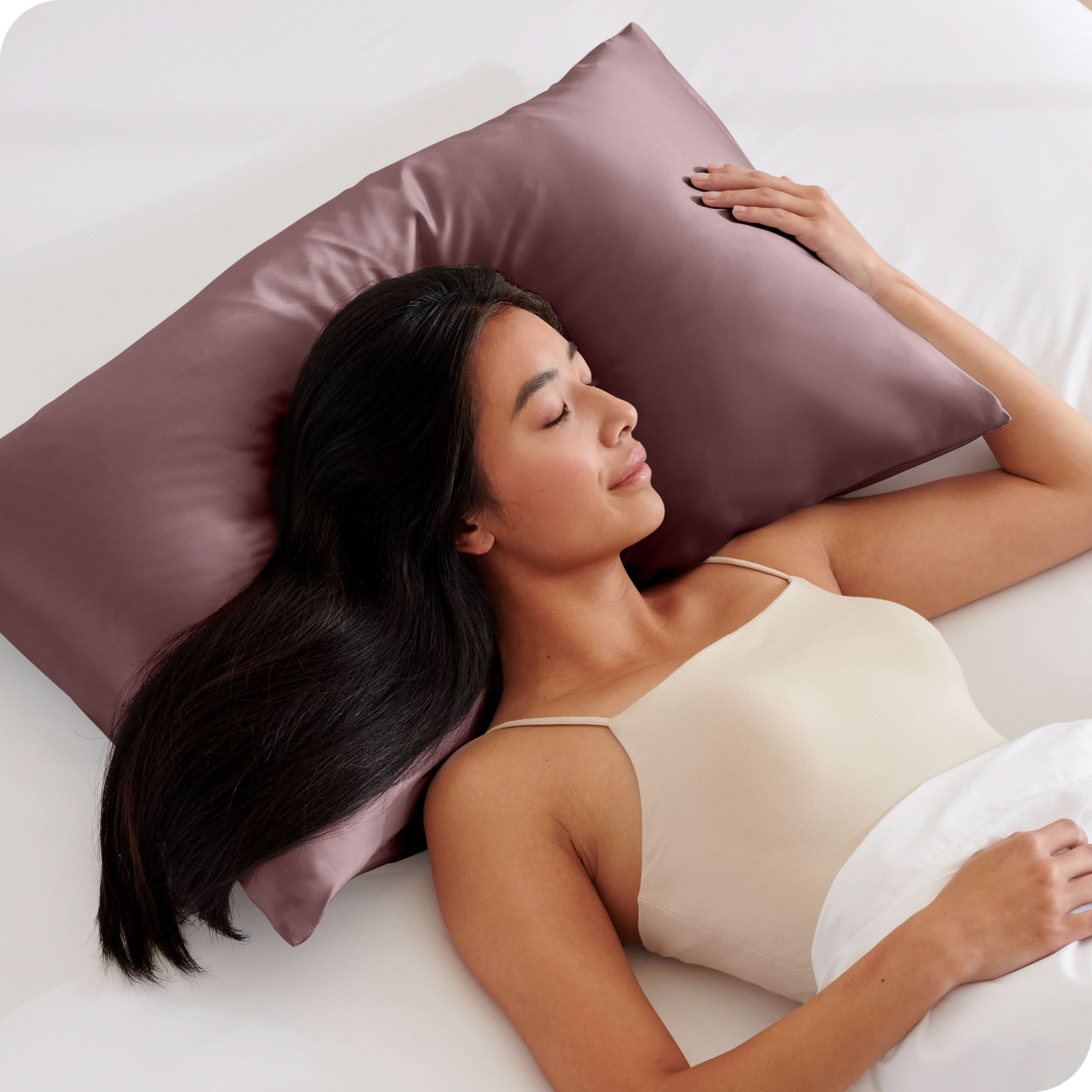 A woman is sleeping on a pillow with a satin pillowcase