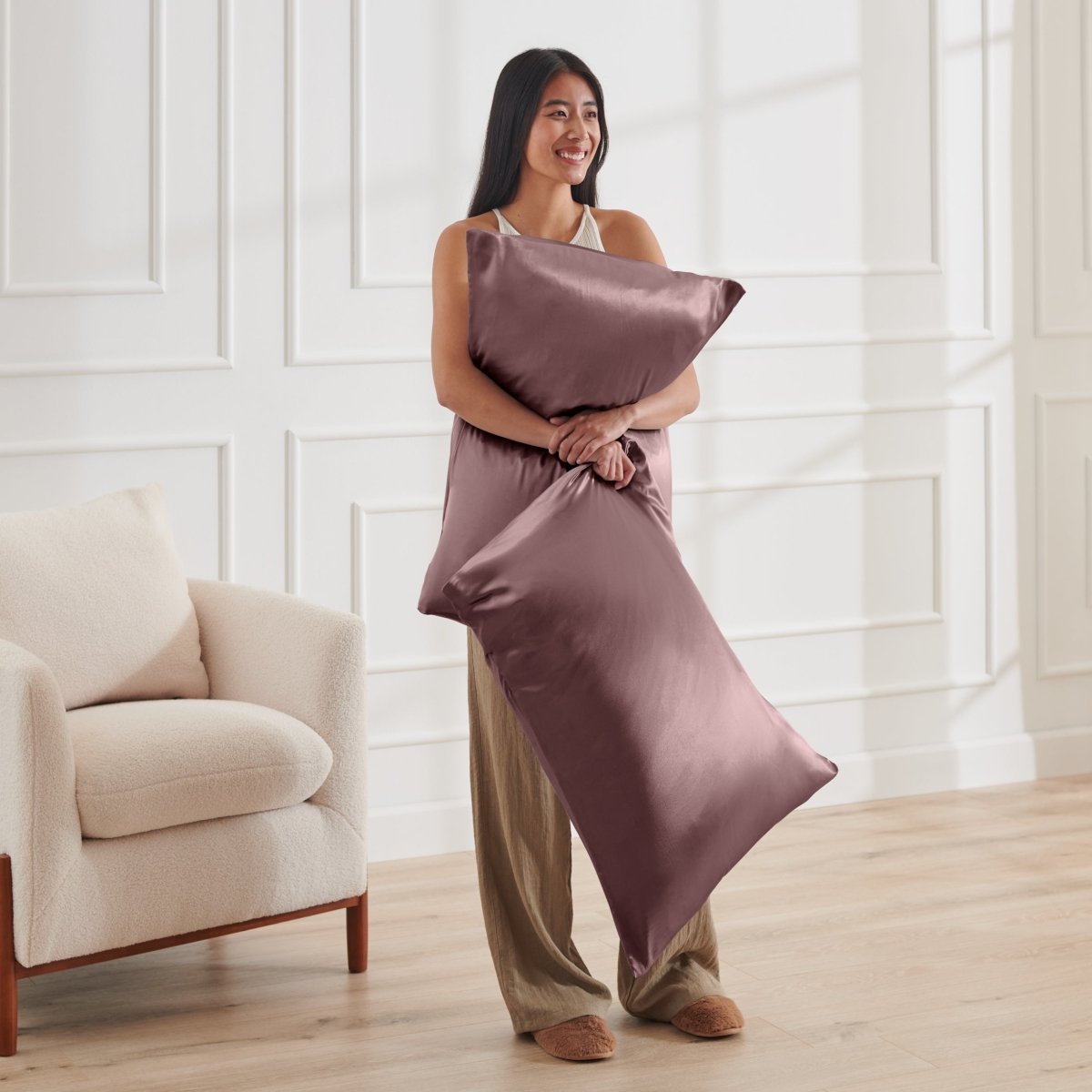 Woman holding 2 pillows with satin pillowcases on them