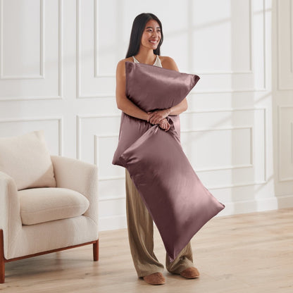 Woman holding 2 pillows with satin pillowcases on them