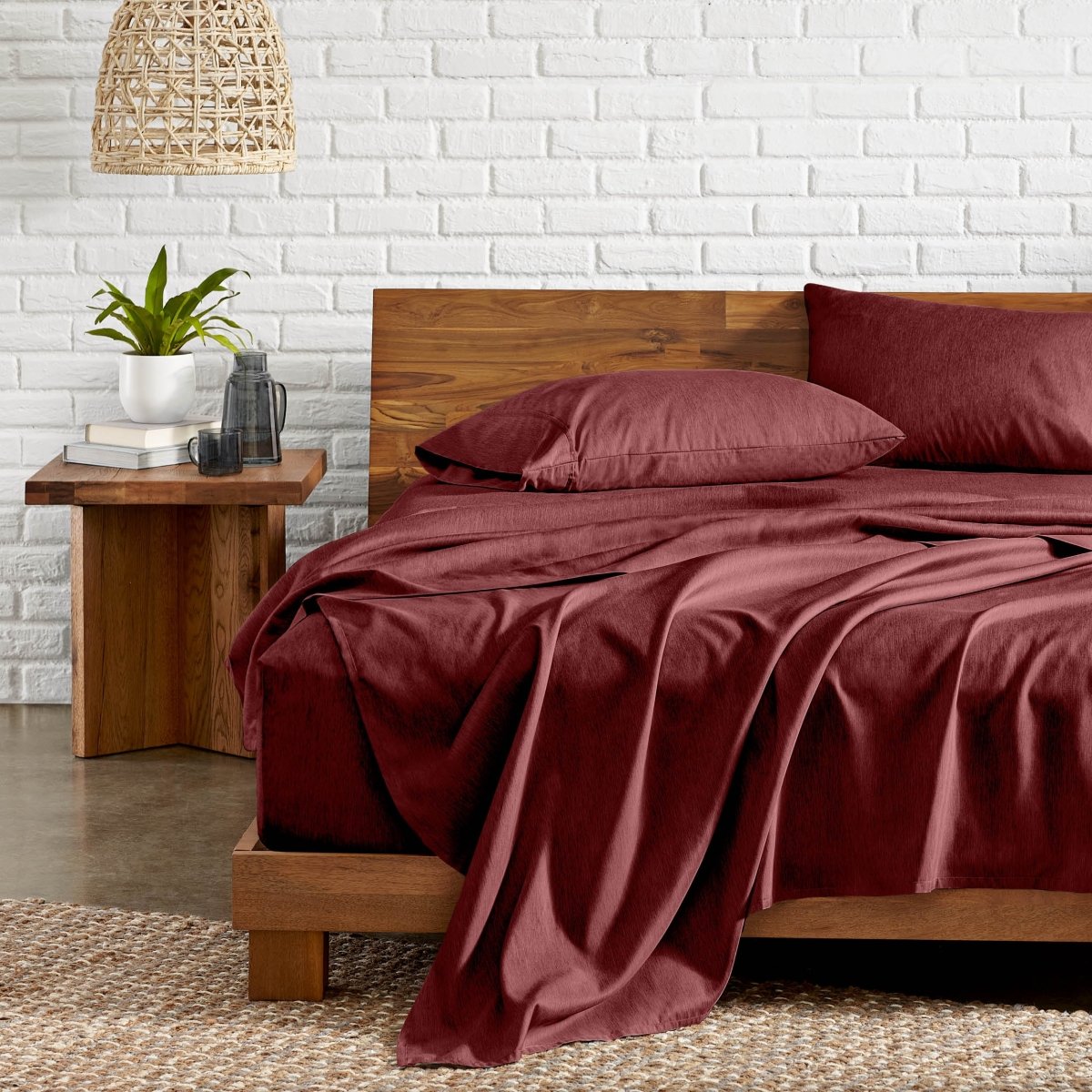 Bedroom with wooden bed, nightstand, and white brick wall.