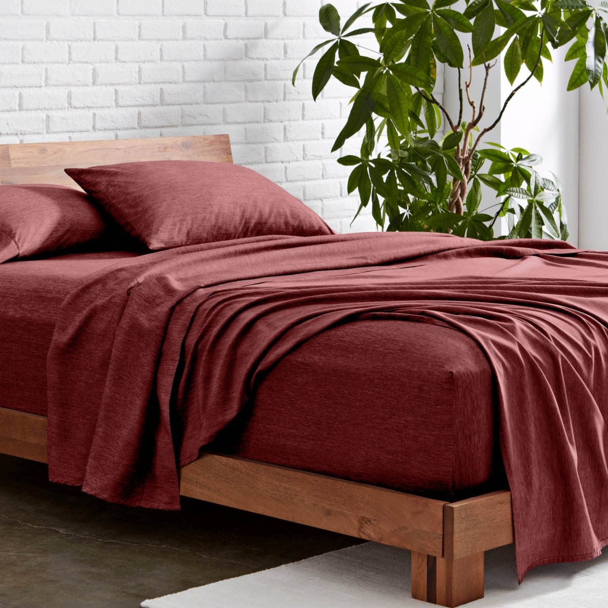 Microfiber sheet set on a wooden bed with a plant in the background