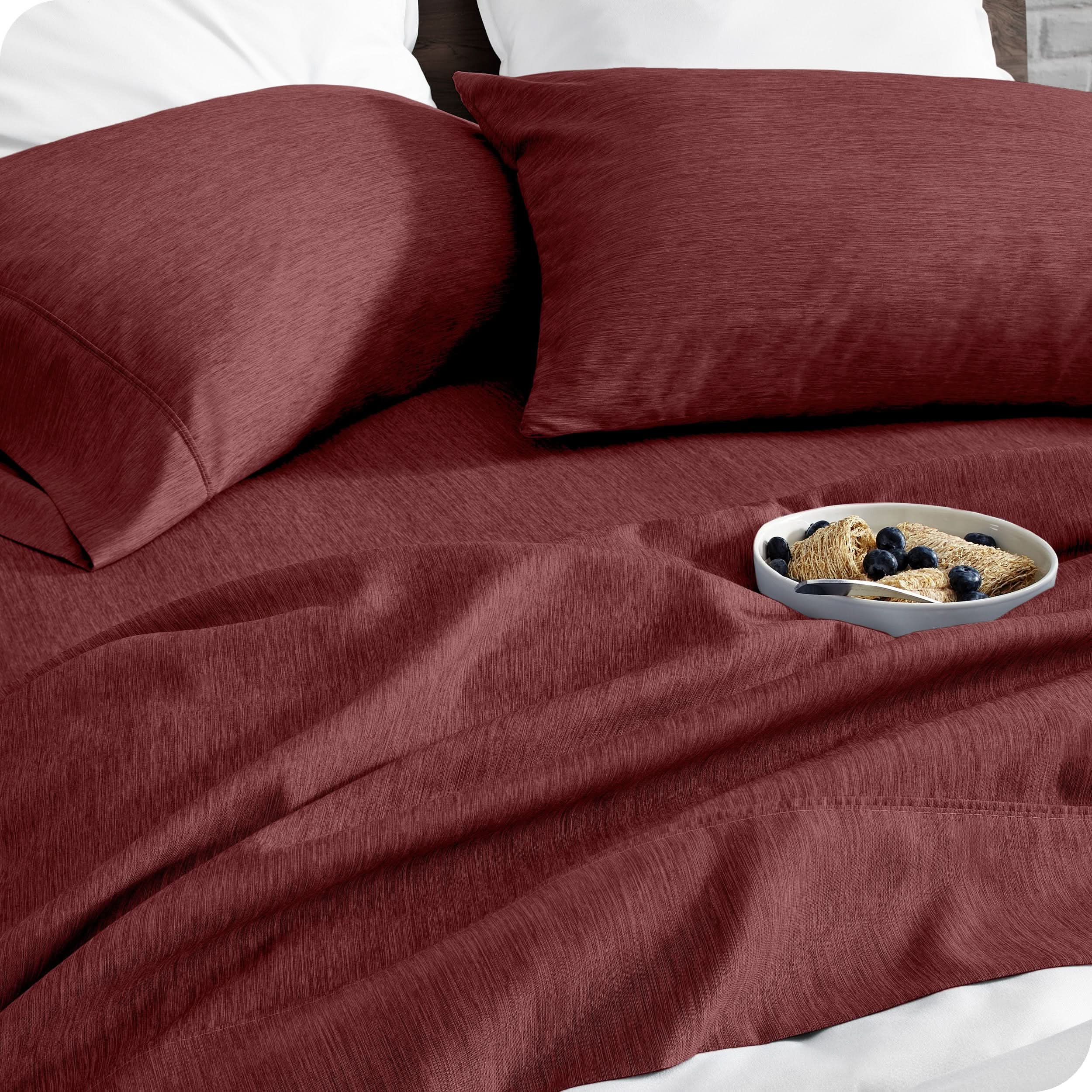 A bed made with sheets. A cereal bowl is on the sheets.