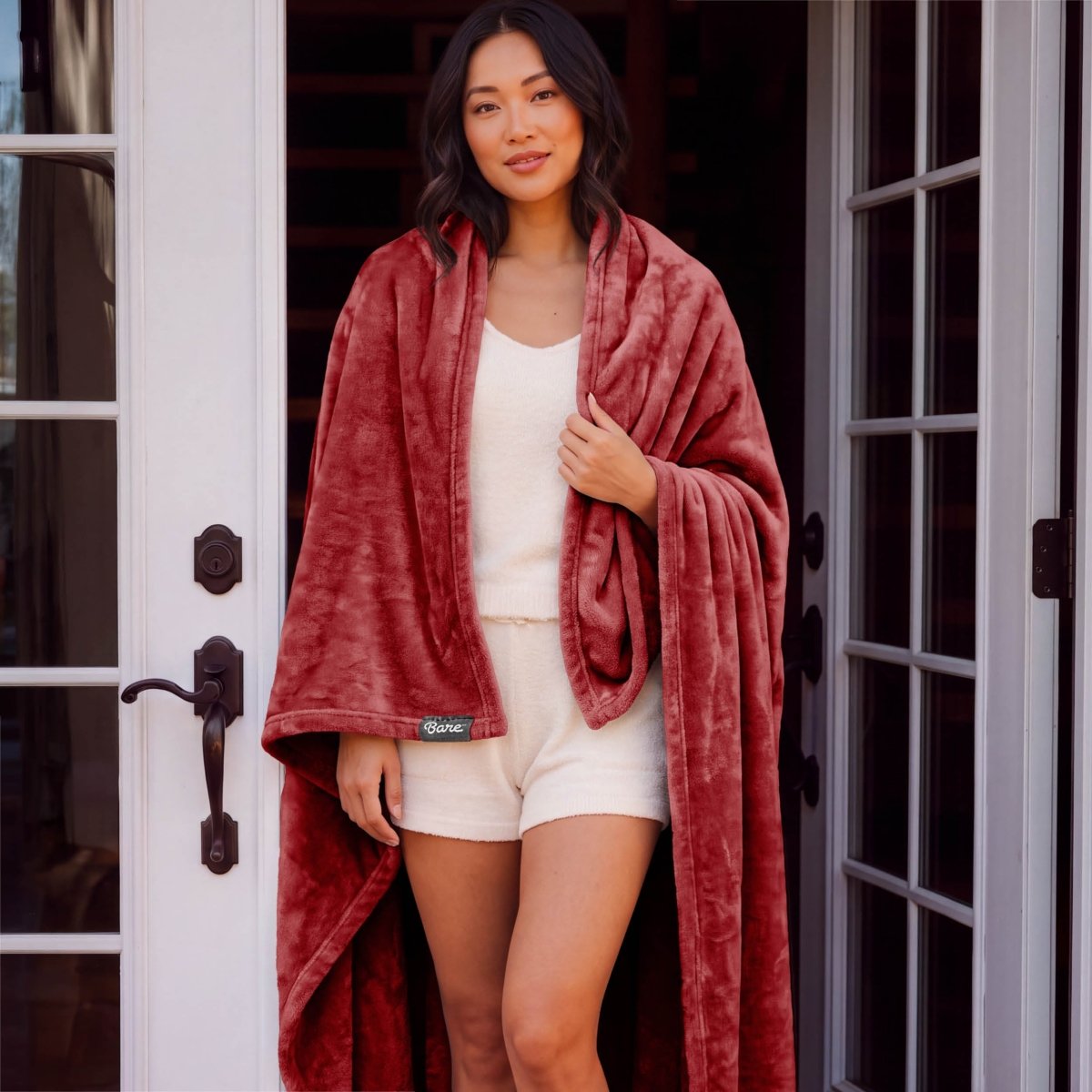 A woman standing with a microplush blanket wrapped around her