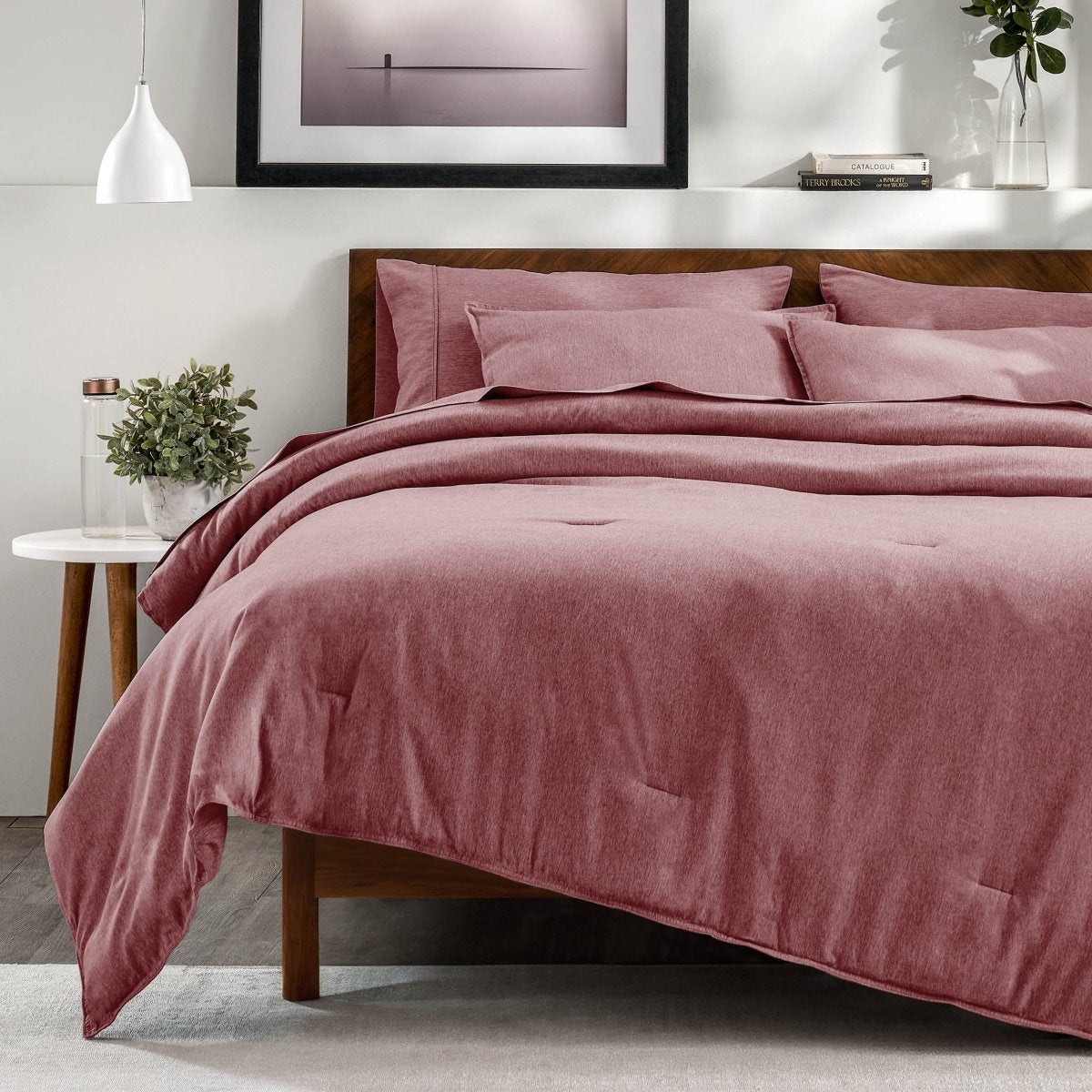 A bedroom with a side table, decor and a neatly made bed