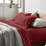 Side view of a bed made with a fitted sheet, pillowcases, and top sheet folded down part way over the duvet cover