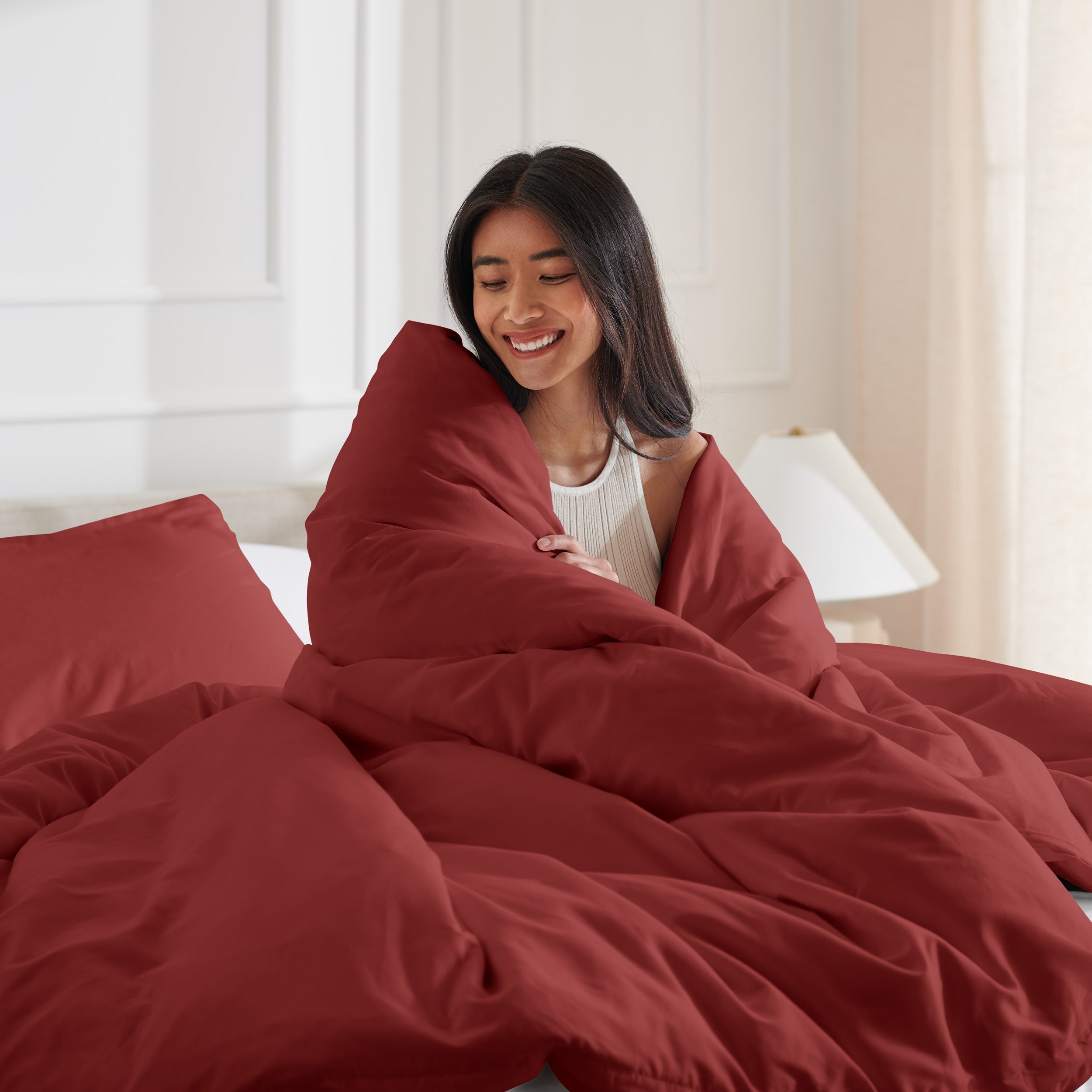 Woman smiling under duvet cover set in a bedroom setting