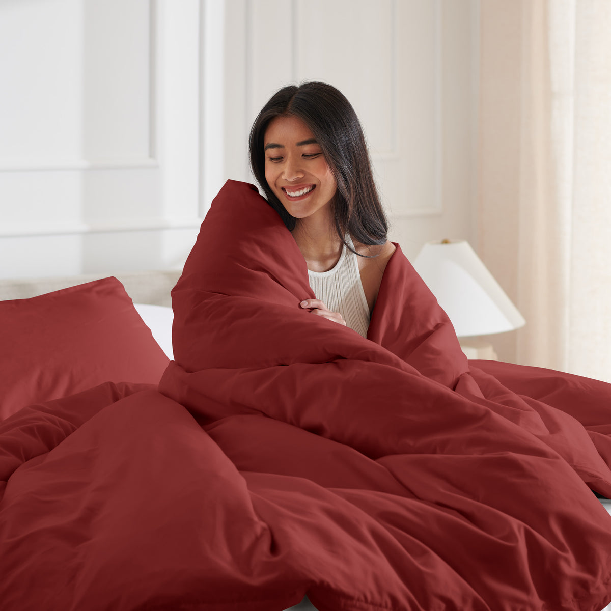 Woman smiling under duvet cover set in a bedroom setting