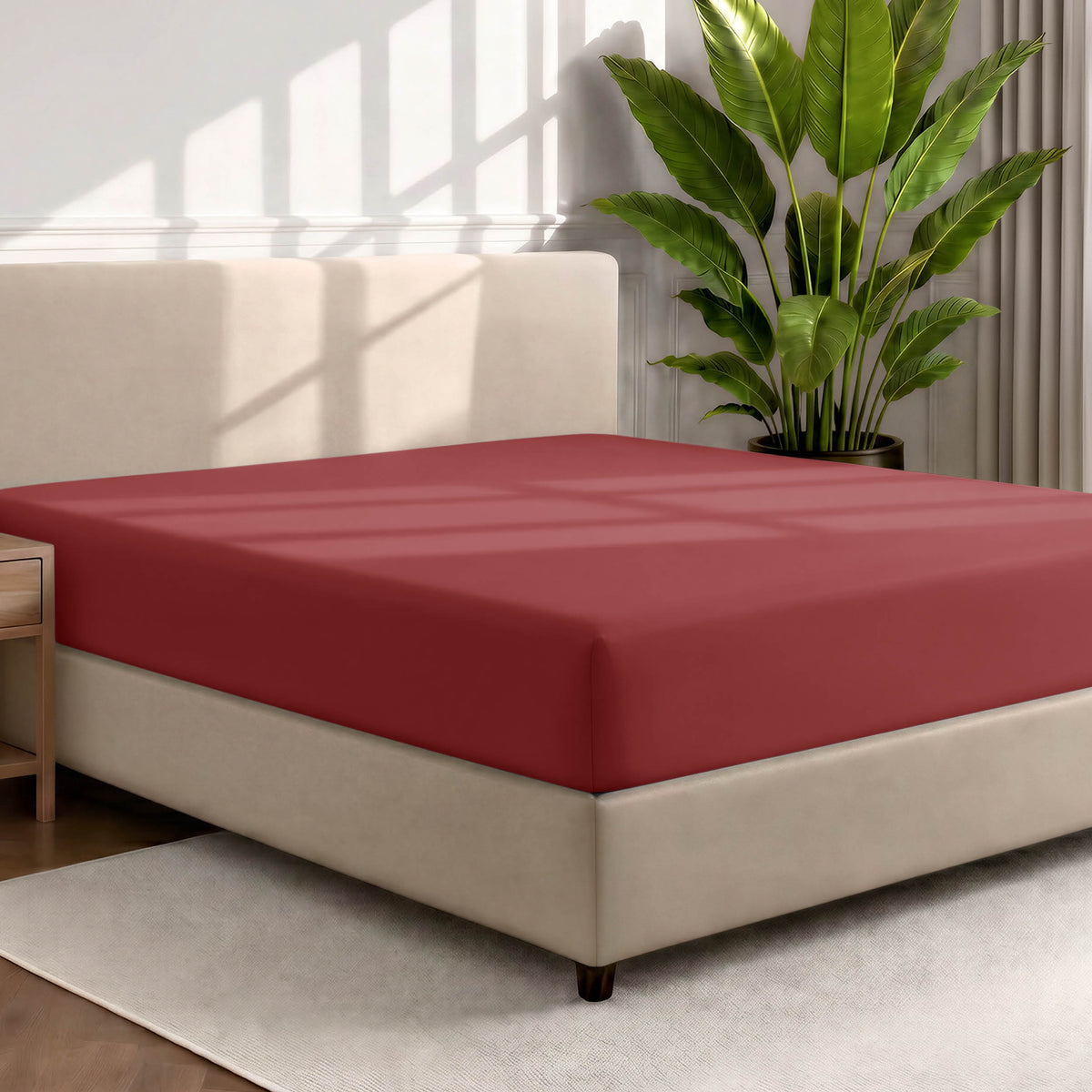 Bed with a fitted sheet in a room with a large plant and rug