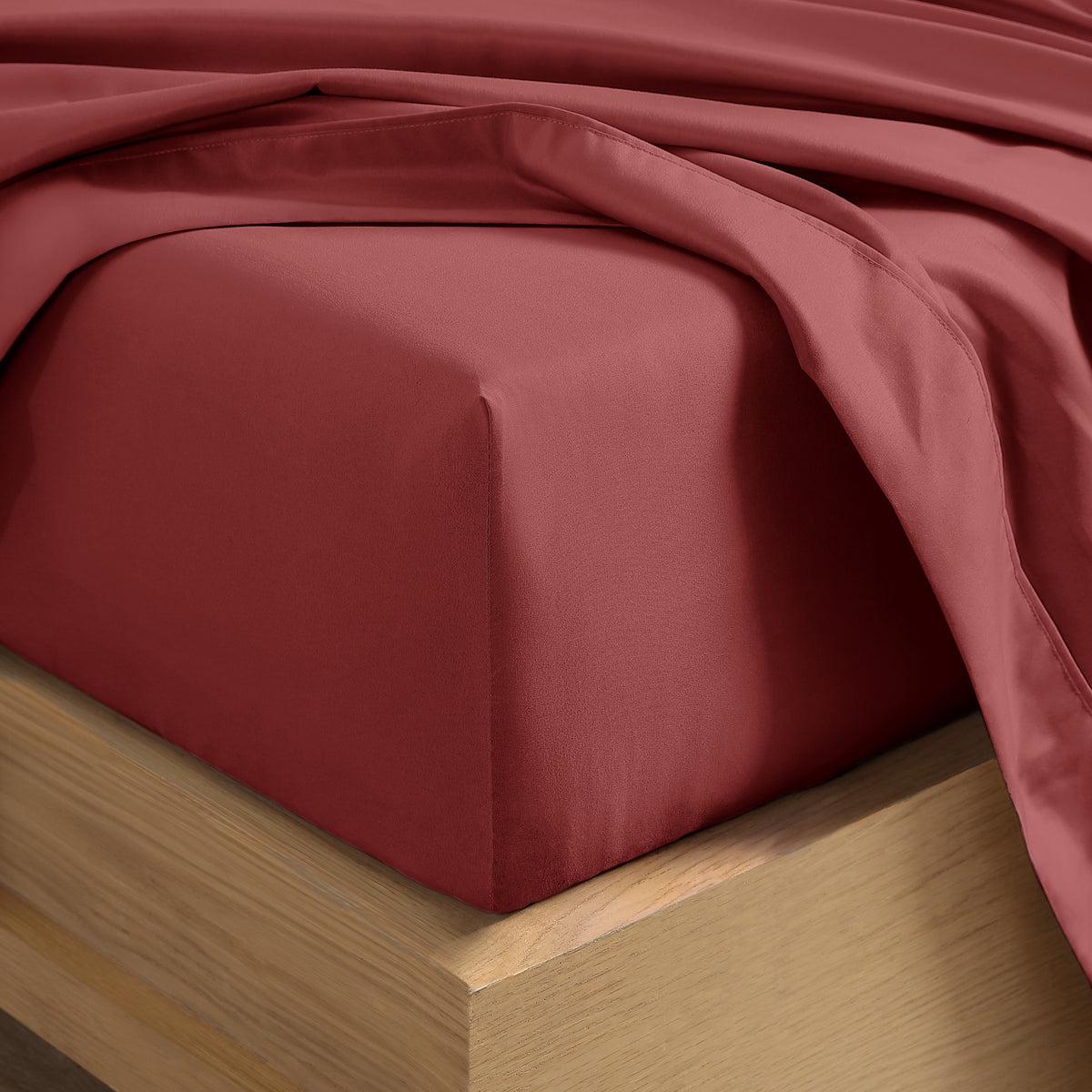 Close up of the corner of a mattress with a fitted sheet and flat sheet on it