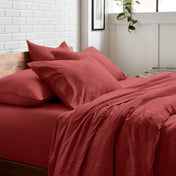 Bedding set on a bed with a white brick wall and window in the background