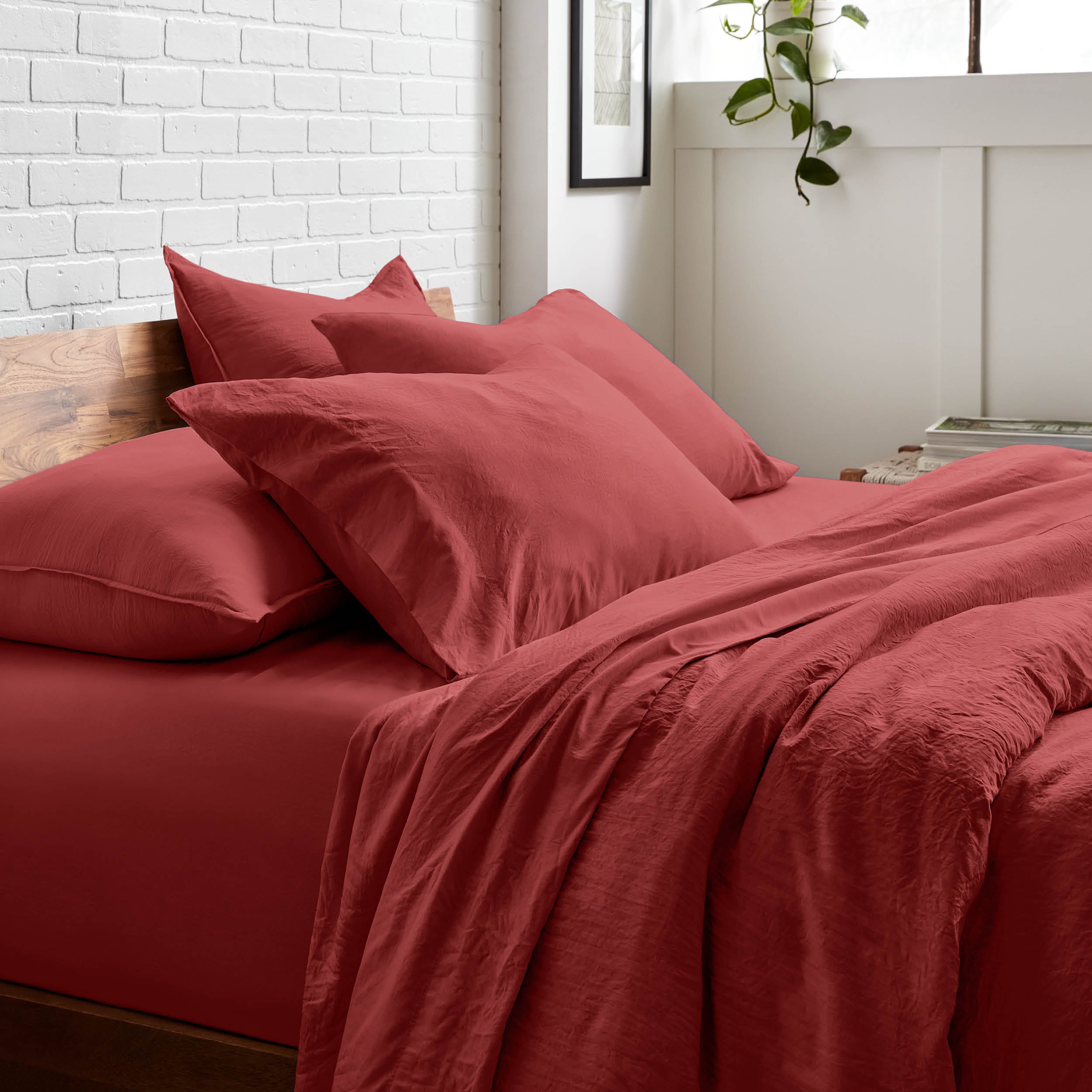 Bedding set on a bed with a white brick wall and window in the background