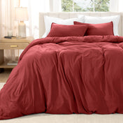Bed with washed bedding and white pillows in a bright room