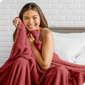 Woman sitting on a bed cuddling with a microplush blanket