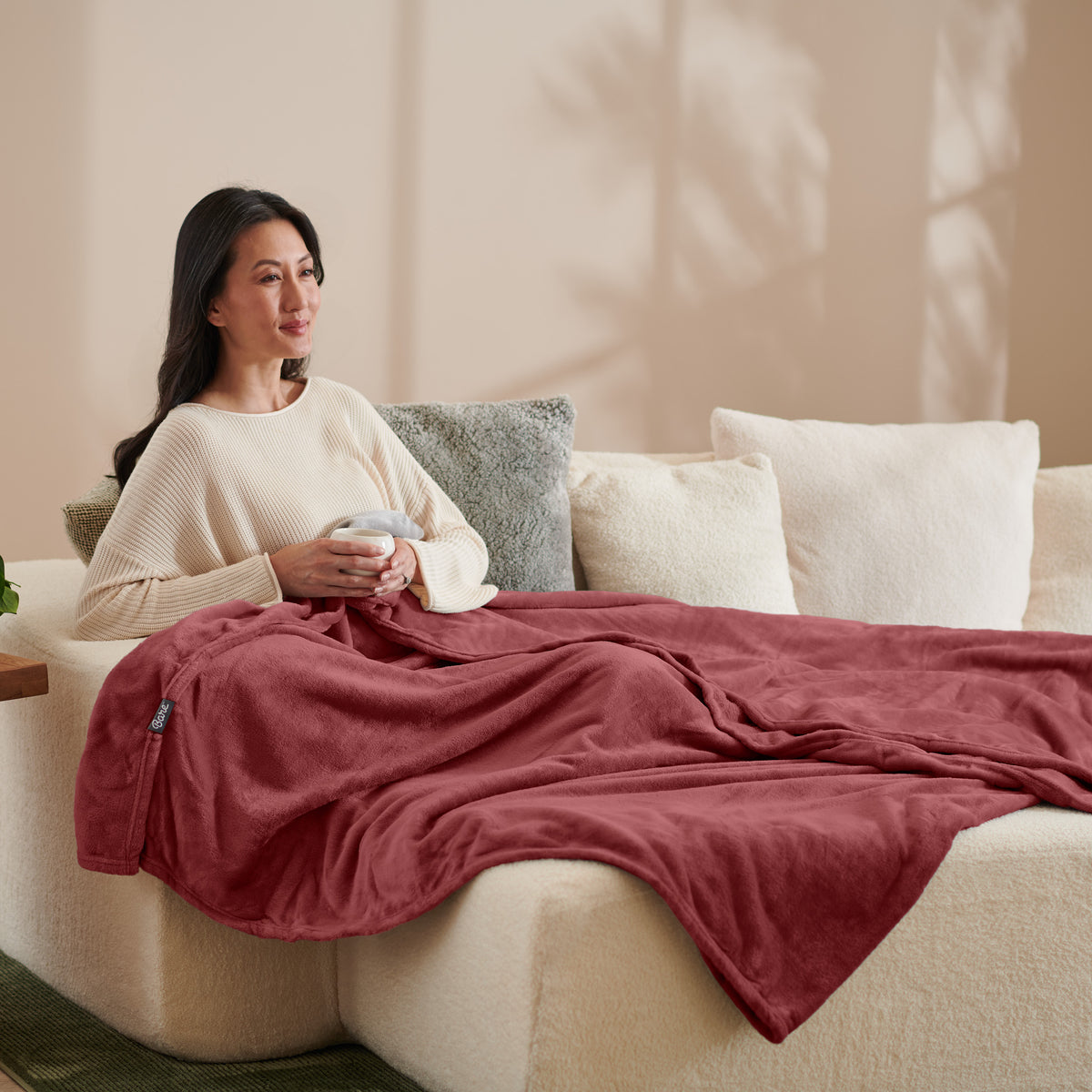 A woman sitting on a couch with a microplush blanket on her lap
