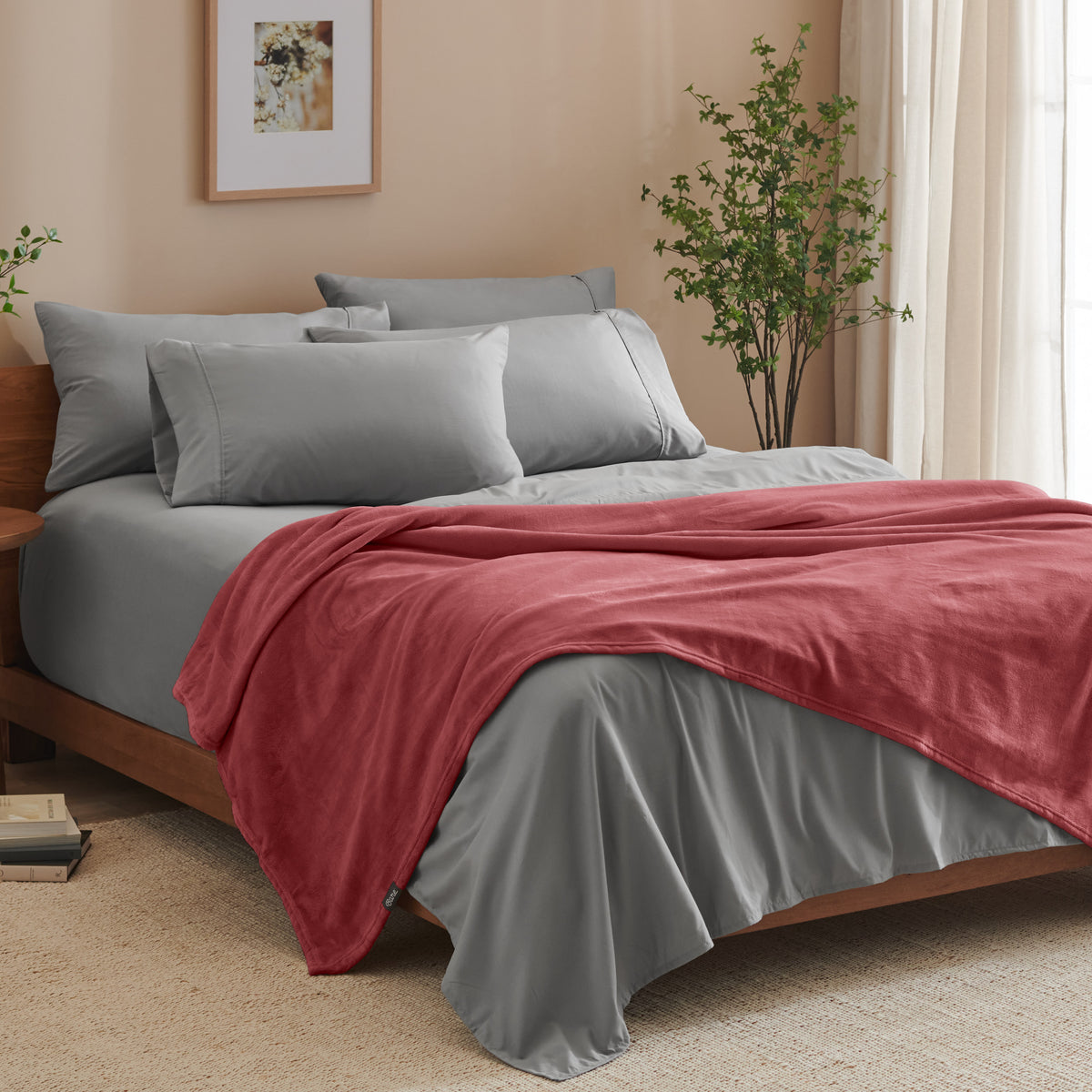 A bed made with grey sheets and a microplush blanket