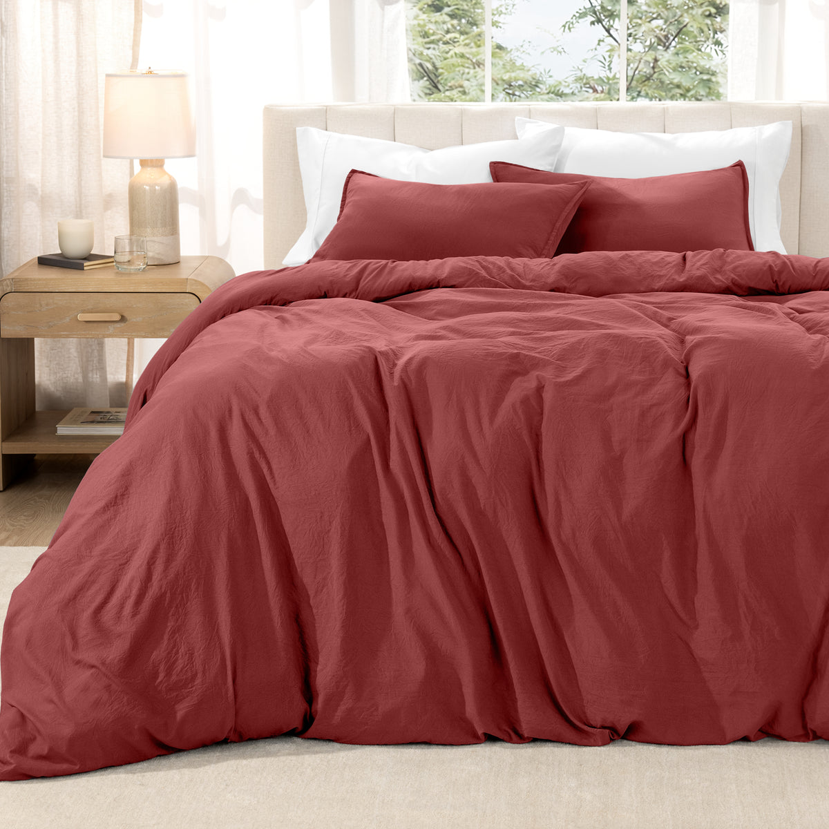 Washed duvet set on a bed in a bright bedroom with a lamp and window.