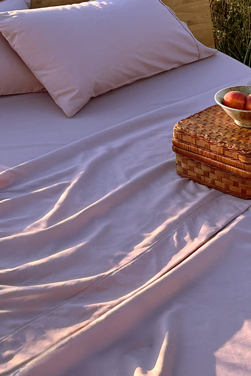 Bed with Rose sheets in a field with a basket of peaches on top